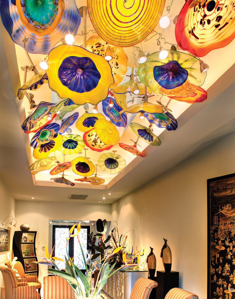 a glass lighting installation that looks like many large colorful flowers attached to the ceiling.