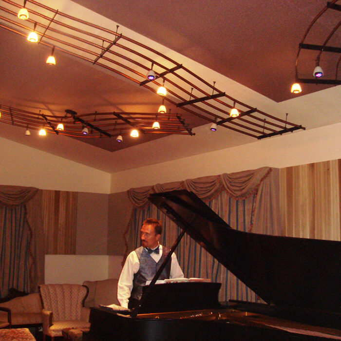 An image of a custom lighting installation that looks like bars of sheet music on the ceiling