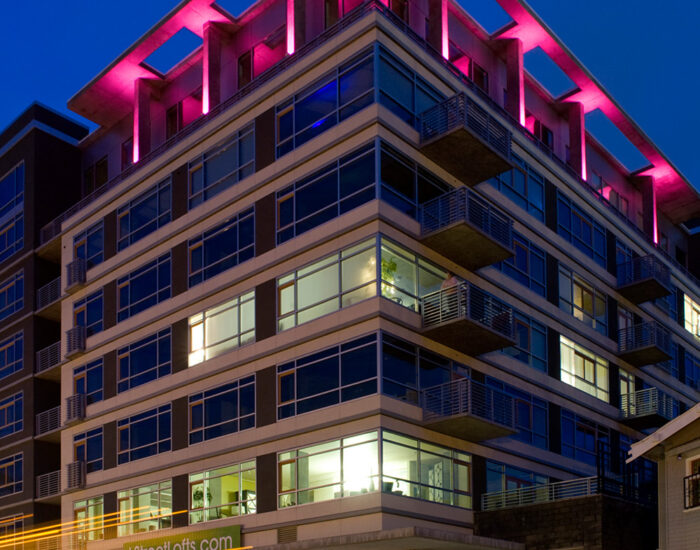 an image of the L Street Lofts taken during the evening with pink light illuminating from the top of the structure