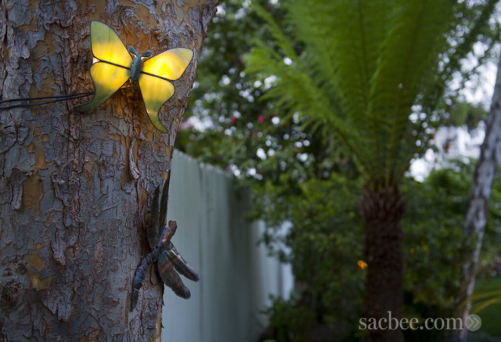 an image of a illuminated butterfly mounted to a tree in a backyard