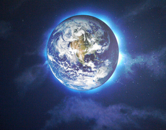 an image of the planet Earth lit from behind on a dark wall of clouds